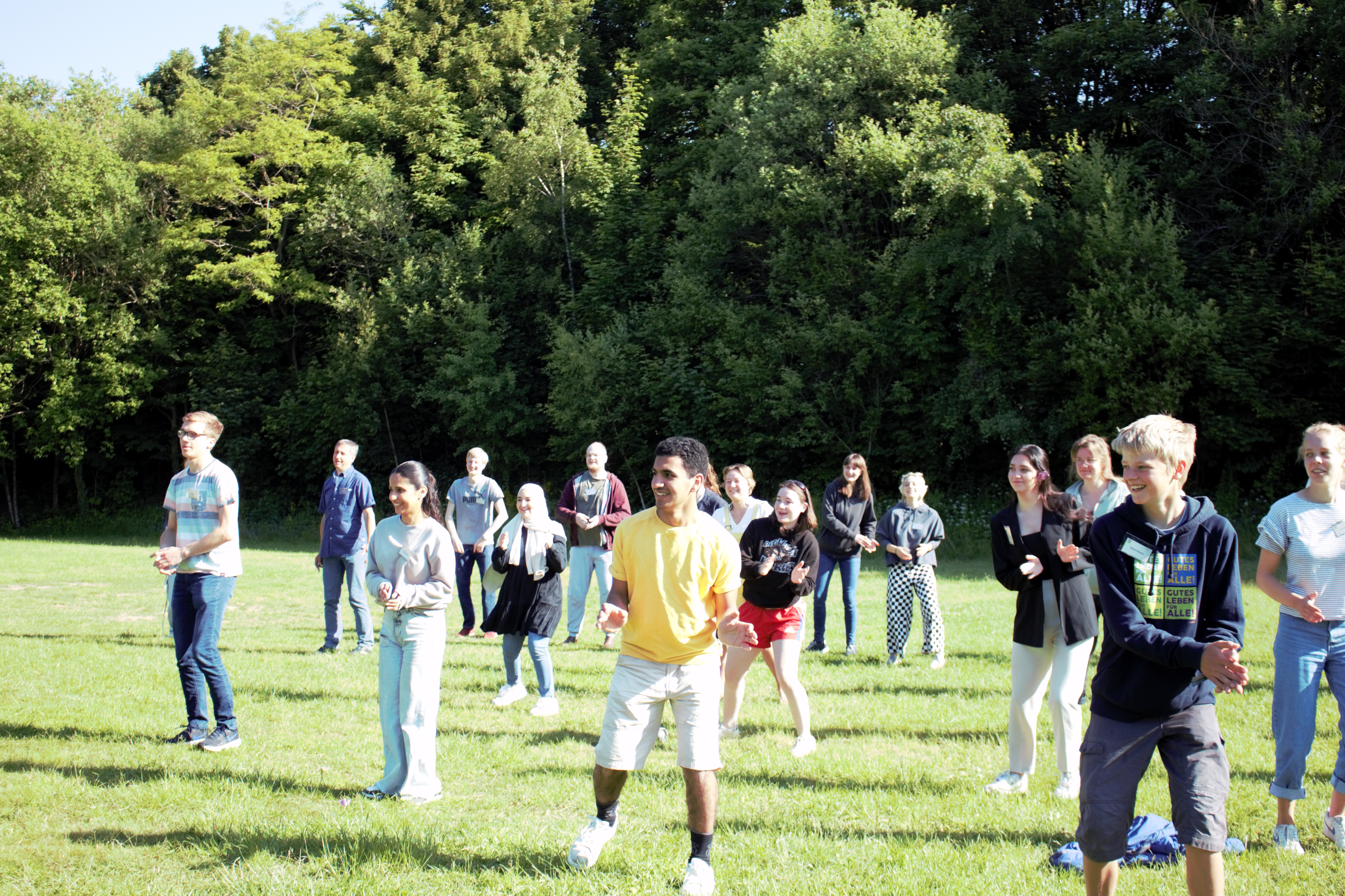 Am Samstag hat die Konferenz mit einem sportlichen Start in den Tag begonnen. Auf dem Bild sind Teilnehmende der Konferenz zu sehen, wie sie auf der Wiese Sport treiben.