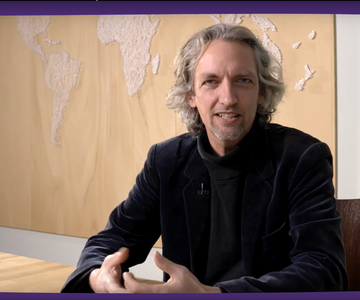 Thomas Hohn sitzt in seinem Büro vor einer Weltkarte