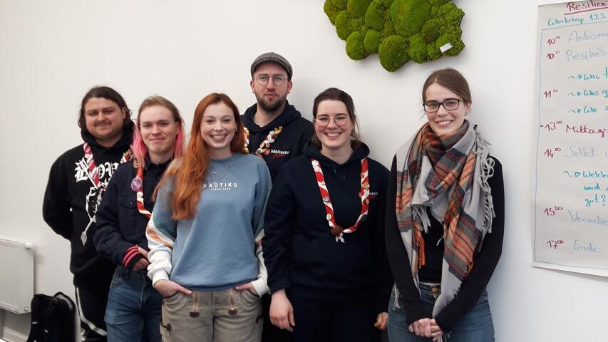 6 junge Menschen, die vor einer Flipchart-Wand stehen
