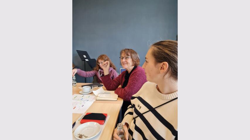 3 Personen sitzen an einem Tisch und sprechen miteinander