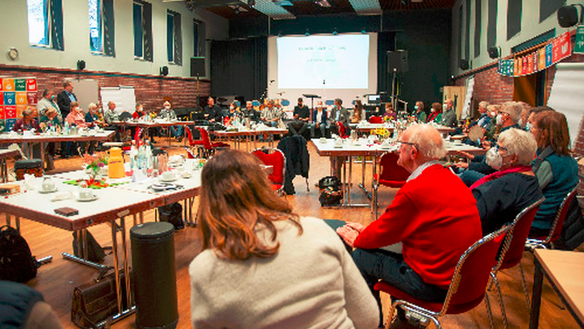 Foto von einer Sitzung des Runden Tisches, an vielen Tischen sitzen Menschen und diskutieren