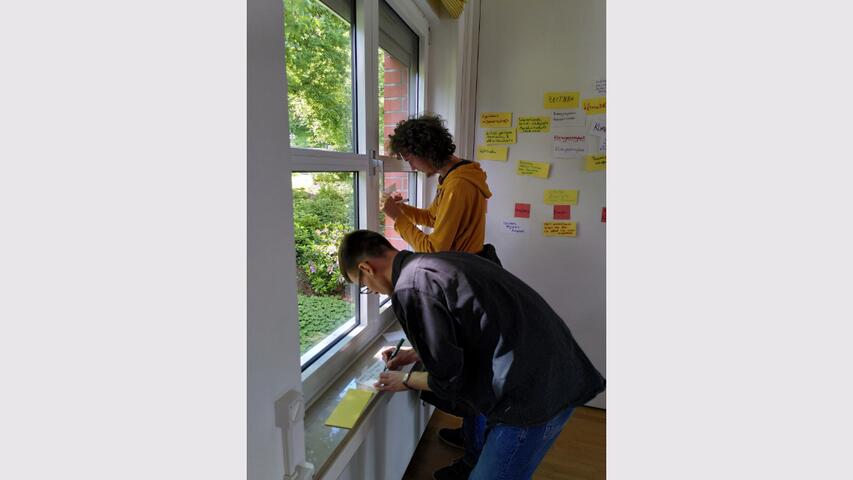 Zwei Personen schreiben Gedanken auf Moderationskarten