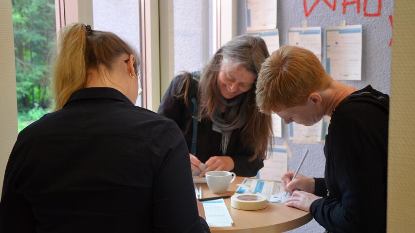 Teilnehmende füllen Steckbriefe für die &quot;Who are you?&quot;-Wand aus