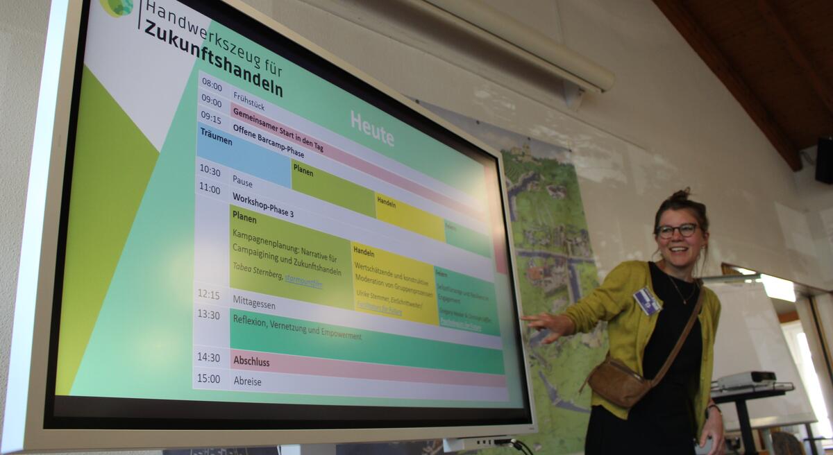 Marie Heitfeld erklärt den Teilnehmenden das Programm für einen Workshop im Begleitrogramm Handwerkszeug für Zukunftshandeln.