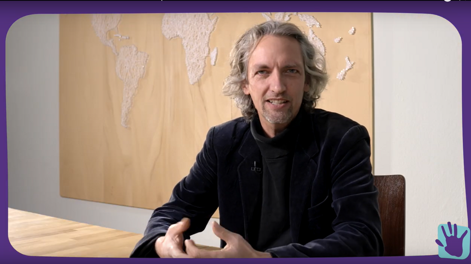 Thomas Hohn sitzt in seinem Büro vor einer Weltkarte